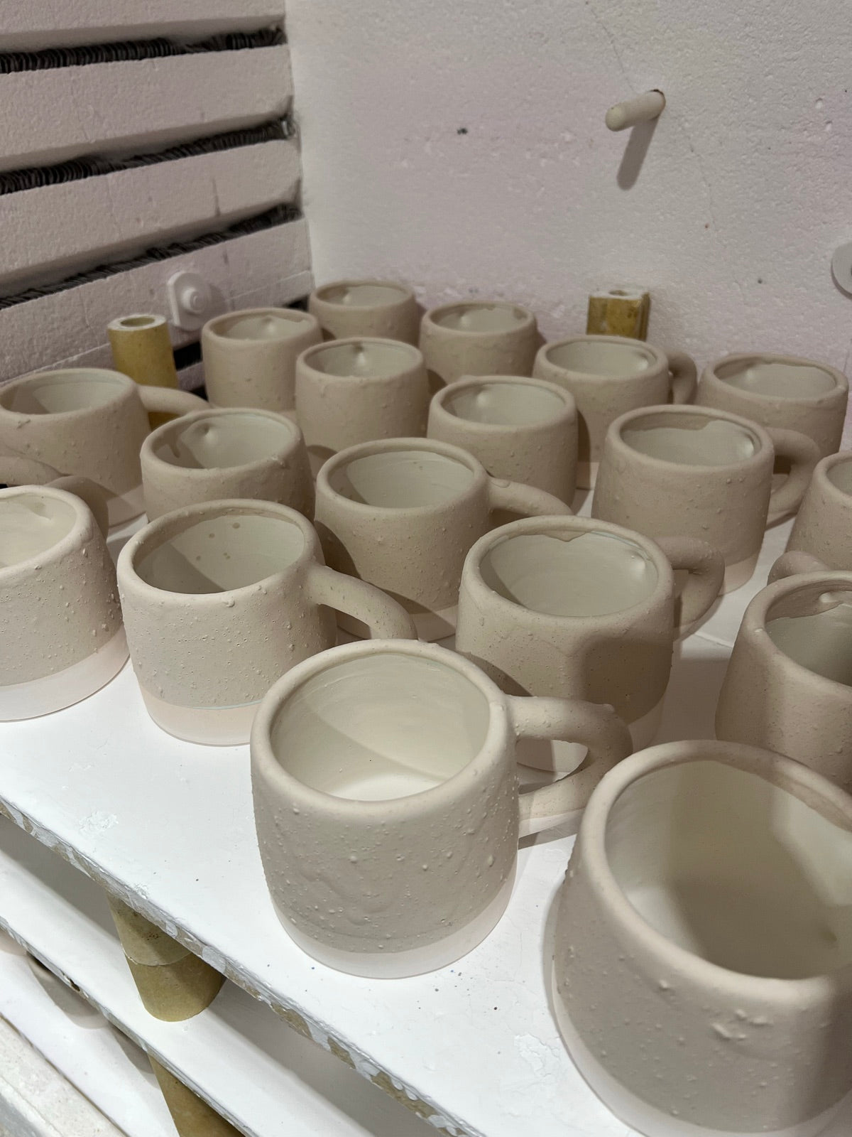 Unglazed handmade mugs on a kiln shelf, ready for firing to cone 6 in Rhiannon Gill's Bellambi studio