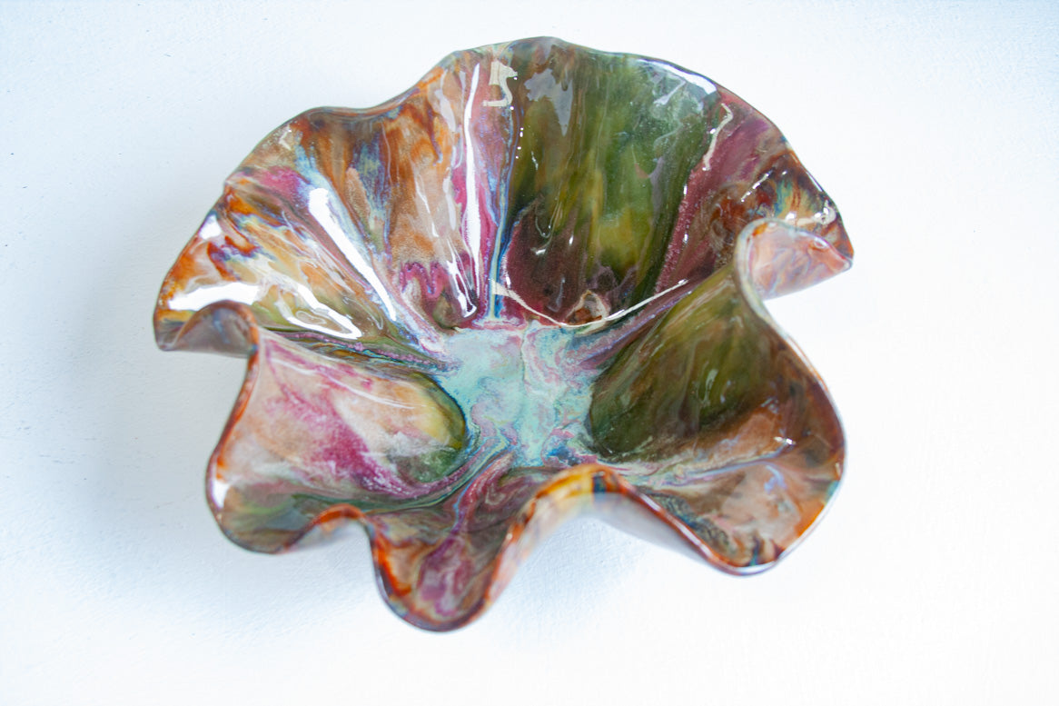 Handmade dark clay oyster serving bowl with a ruffled rim, glazed in green, amber and pink
