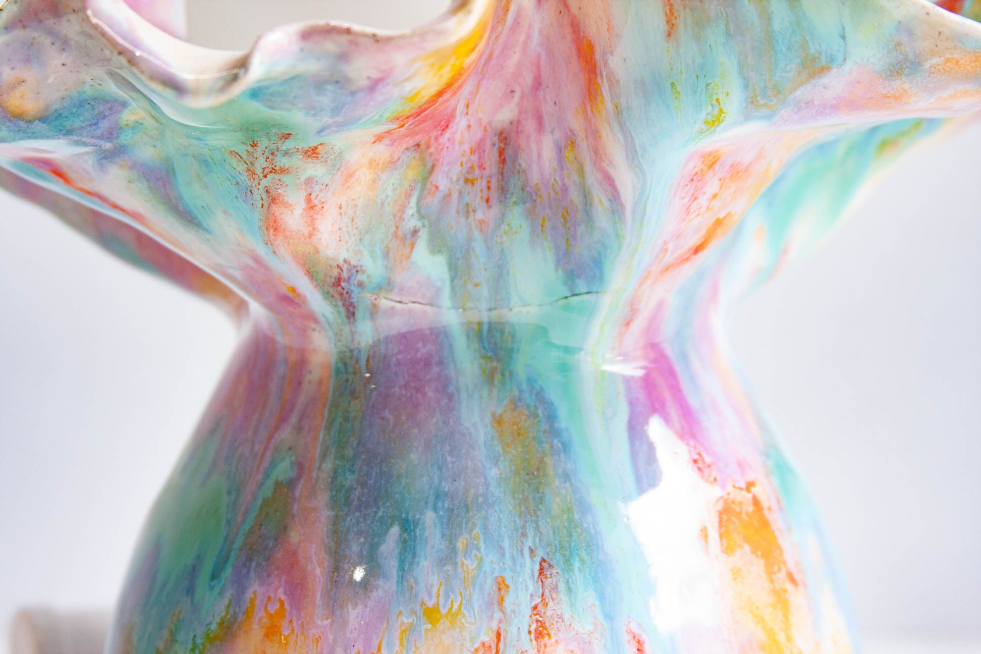 Close-up of the body of a handmade ceramic Oyster table lamp showing a fine crack running across the glaze, the flaw this piece is sold as seconds for.