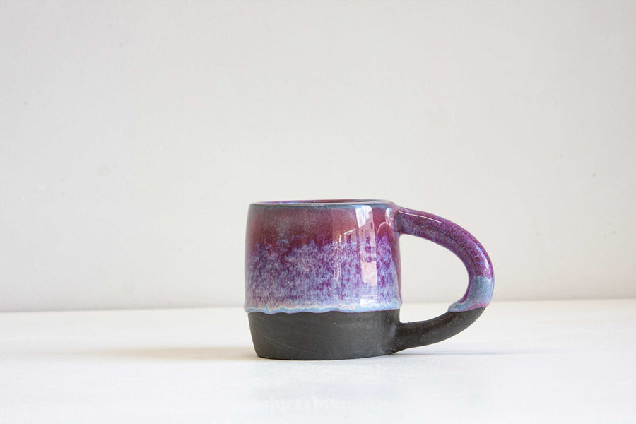 Handmade ceramic black clay mug glazed in purple and blue.