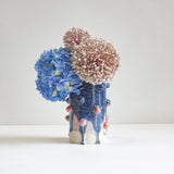 Decorative vase with blue and pink textured top on a white clay body