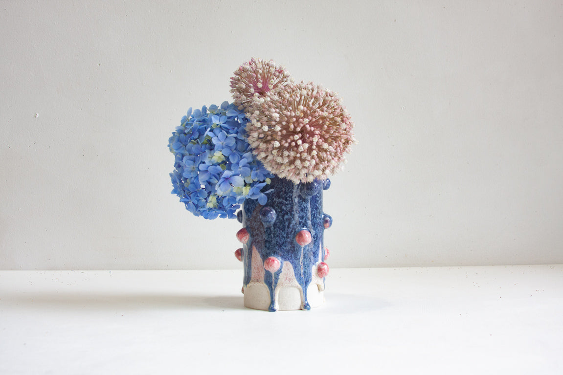 Decorative vase with blue and pink textured top on a white clay body