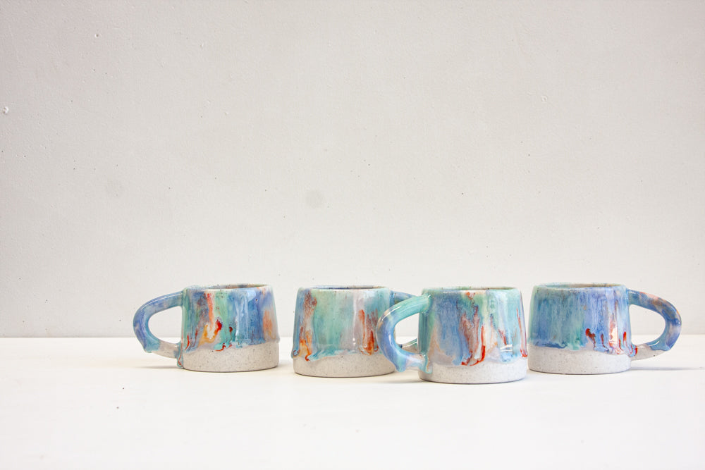 four handmade ceramic mugs on top of a table