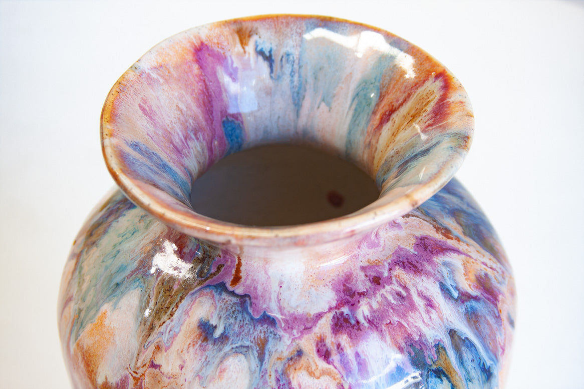 Top-down view into the wide flared rim of handmade ceramic large vase, showing swirling multi-colour pour glaze in pink, purple, blue, teal, brown and amber