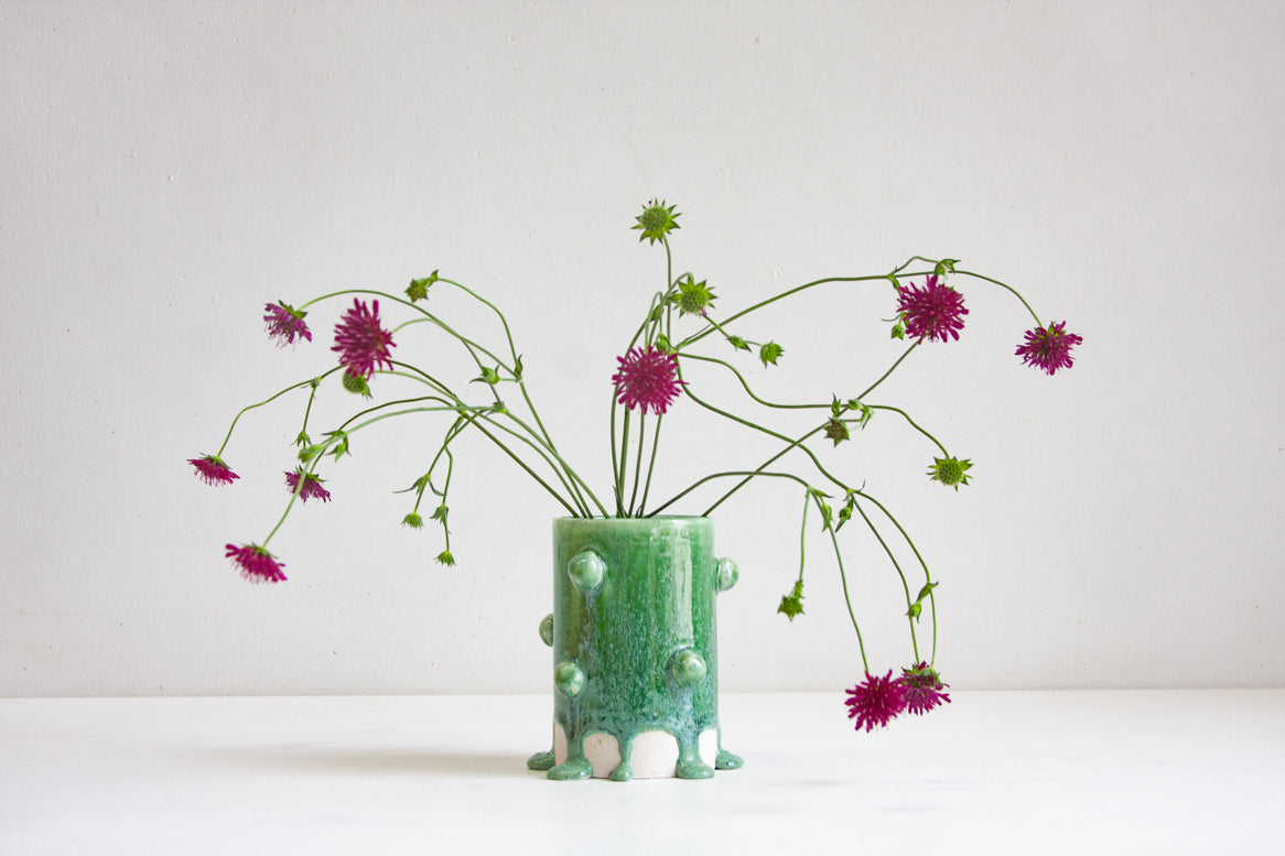 handmade ceramic cylinder vase decorated with small balls glazed in a drippy green glaze