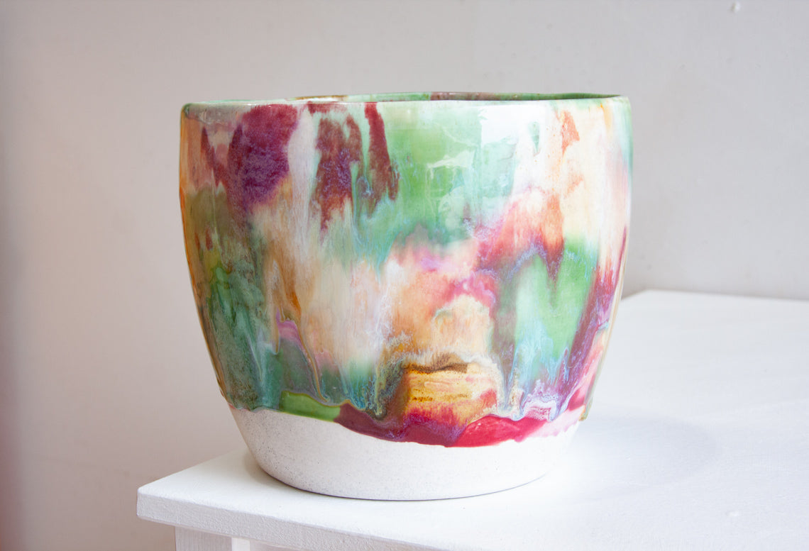 Front view of a handmade ceramic large planter with multicolour brushstroke glaze in green, red, purple, pink, peach and teal, unglazed white stoneware lower third