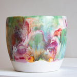 Side view of a handmade ceramic large planter with multicolour brushstroke glaze in green, teal, pink, purple and amber, unglazed white stoneware lower third