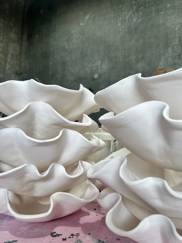 a collection of handmade ceramic serving platters after bisque firing, stacked on each other and ready for glazing 