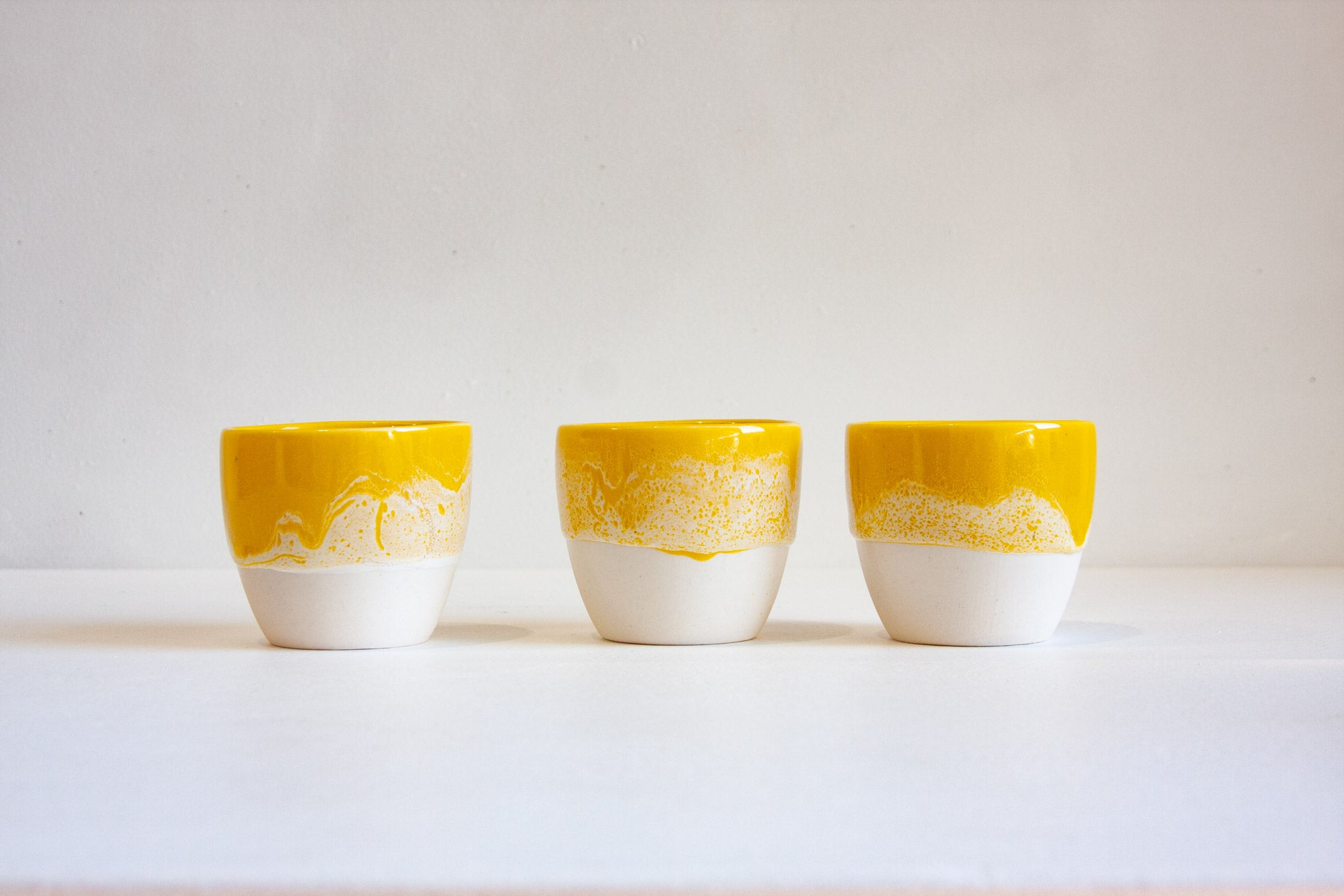 three handmade speckled yellow ceramic cups