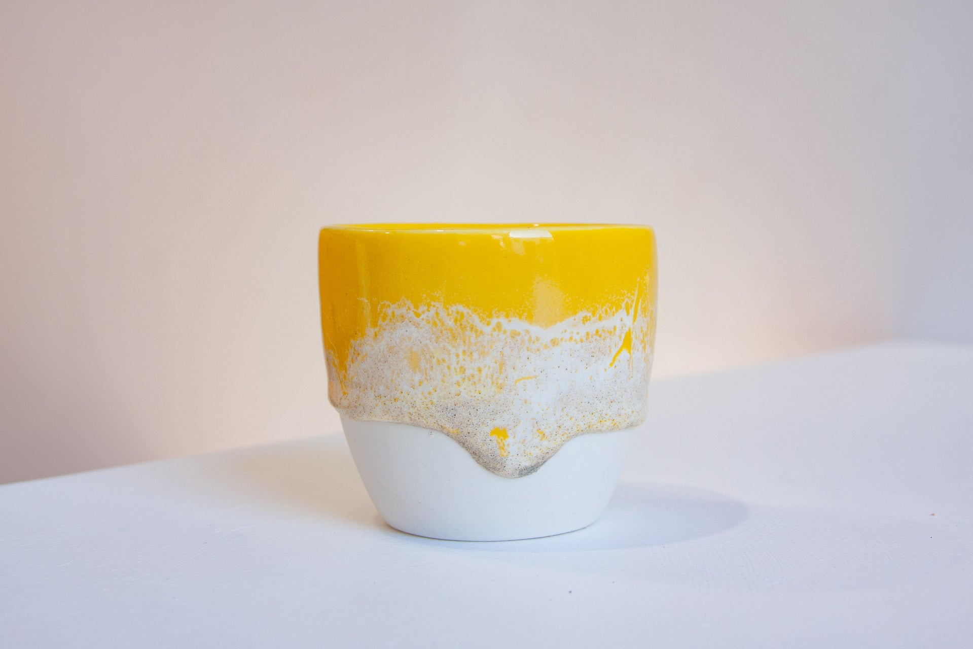 one handmade ceramic yellow glazed cup sitting on a table