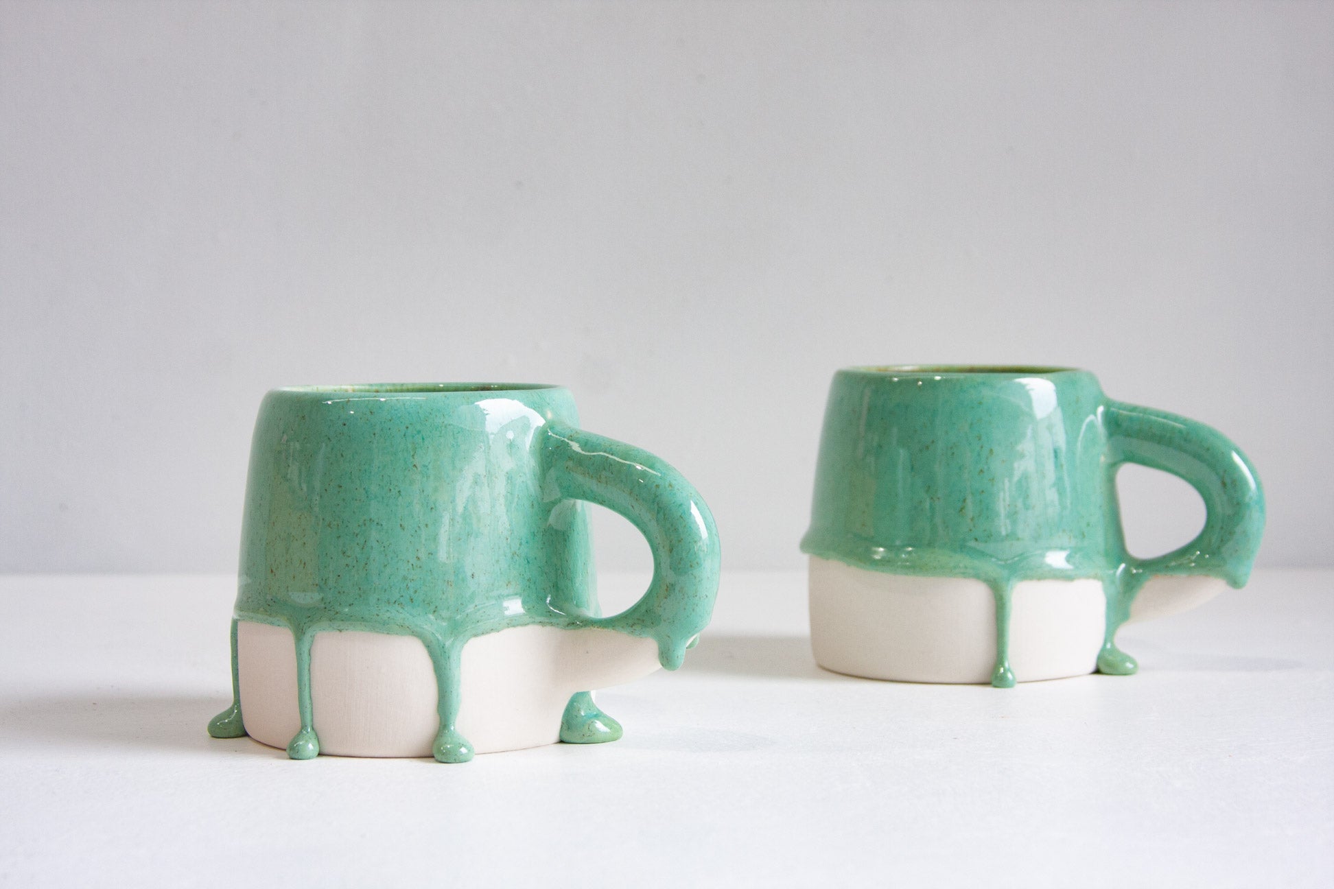 two handmade large ceramic mugs glazed in a drippy green.