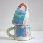 two handmade ceramic mugs, one sitting on top of the other