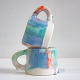 two handmade ceramic mugs, one sitting on top of the other