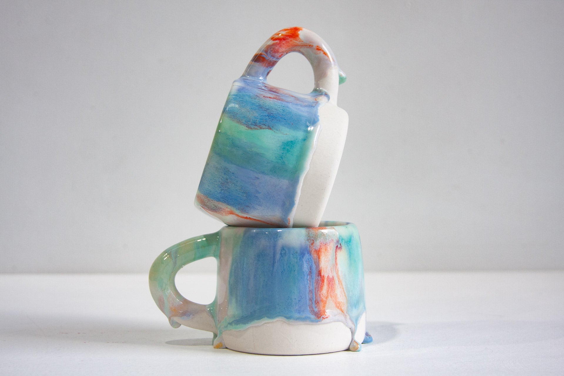 two handmade ceramic mugs, one sitting on top of the other