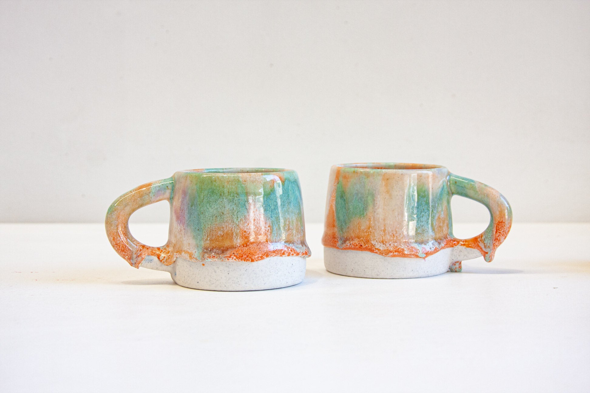 two peach, purple and green ceramic mugs.