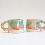 two peach, purple and green ceramic mugs.