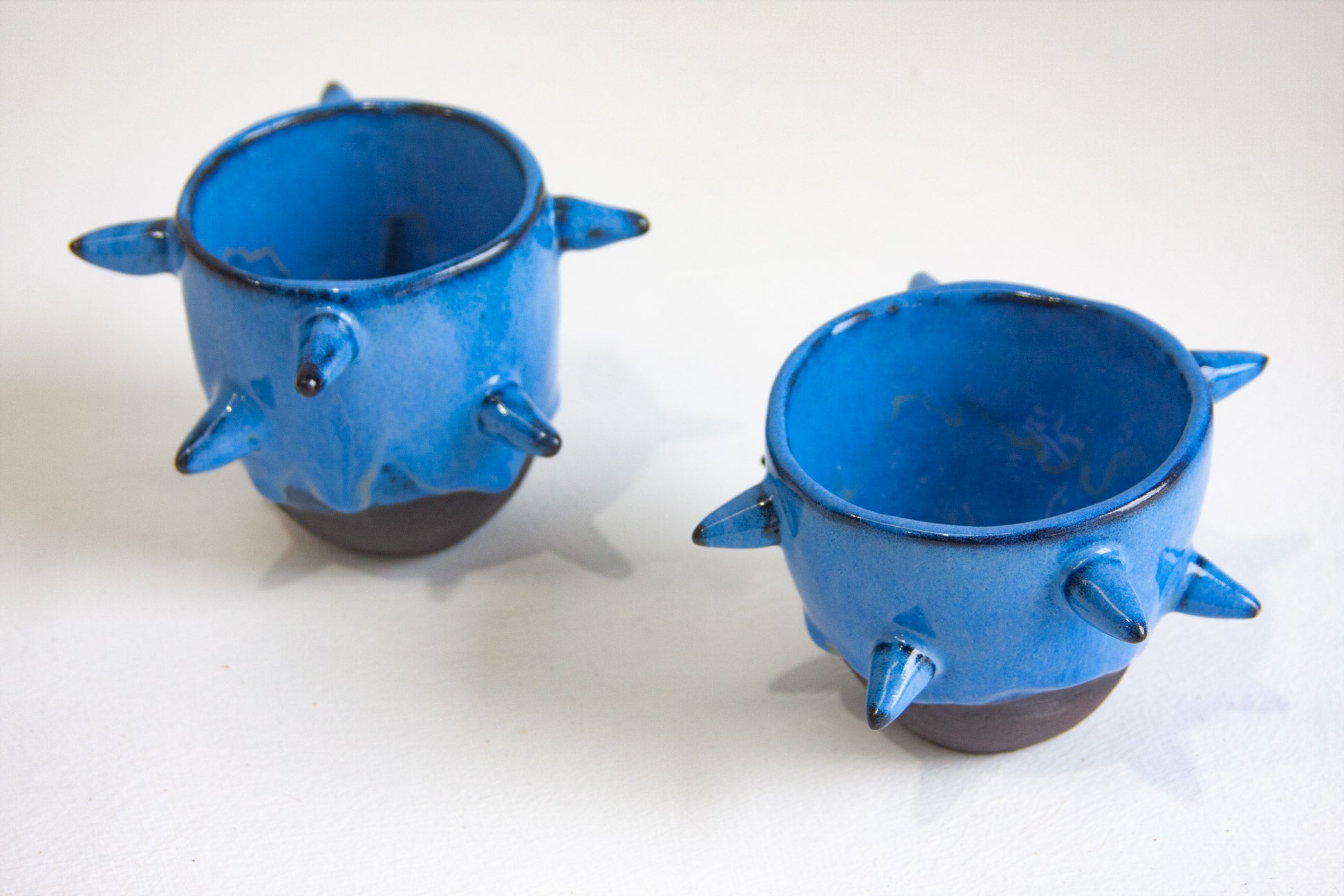 Two blue ceramic cups with spike-like protrusions on a white background
