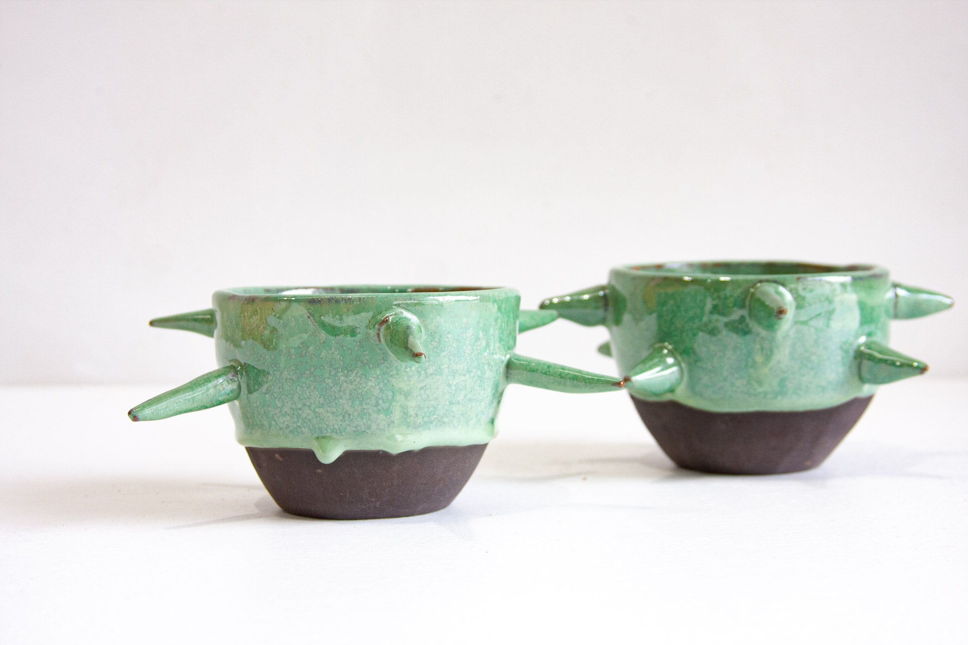 Two green ceramic bowls with textured design on a white background