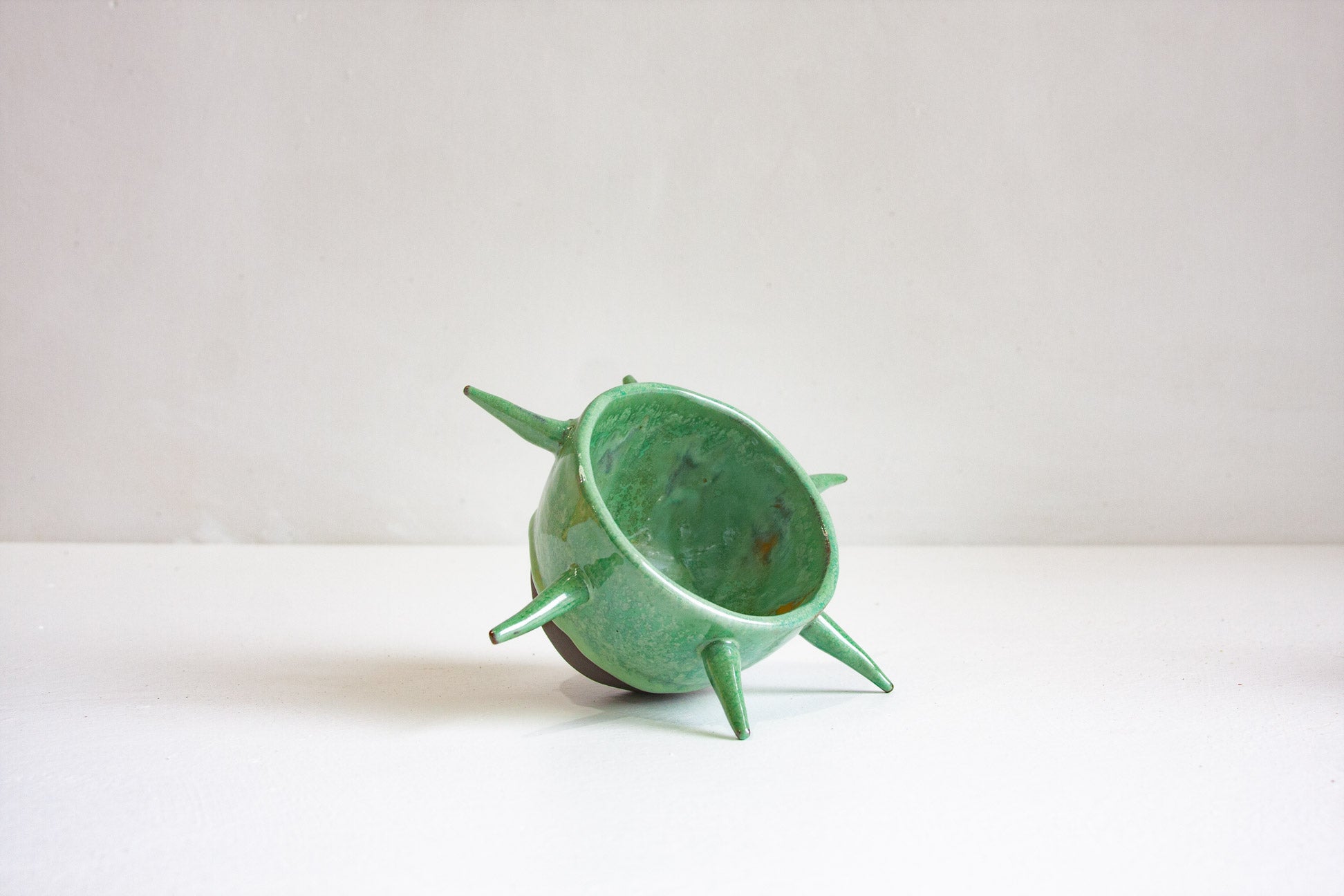 Green ceramic planter with spiky design on a white background