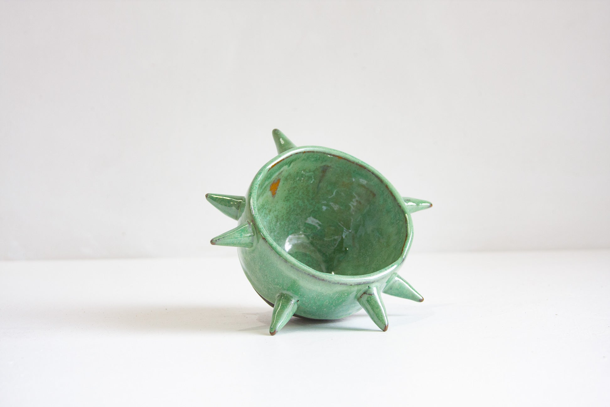 Green ceramic pot with spiky design on a white background