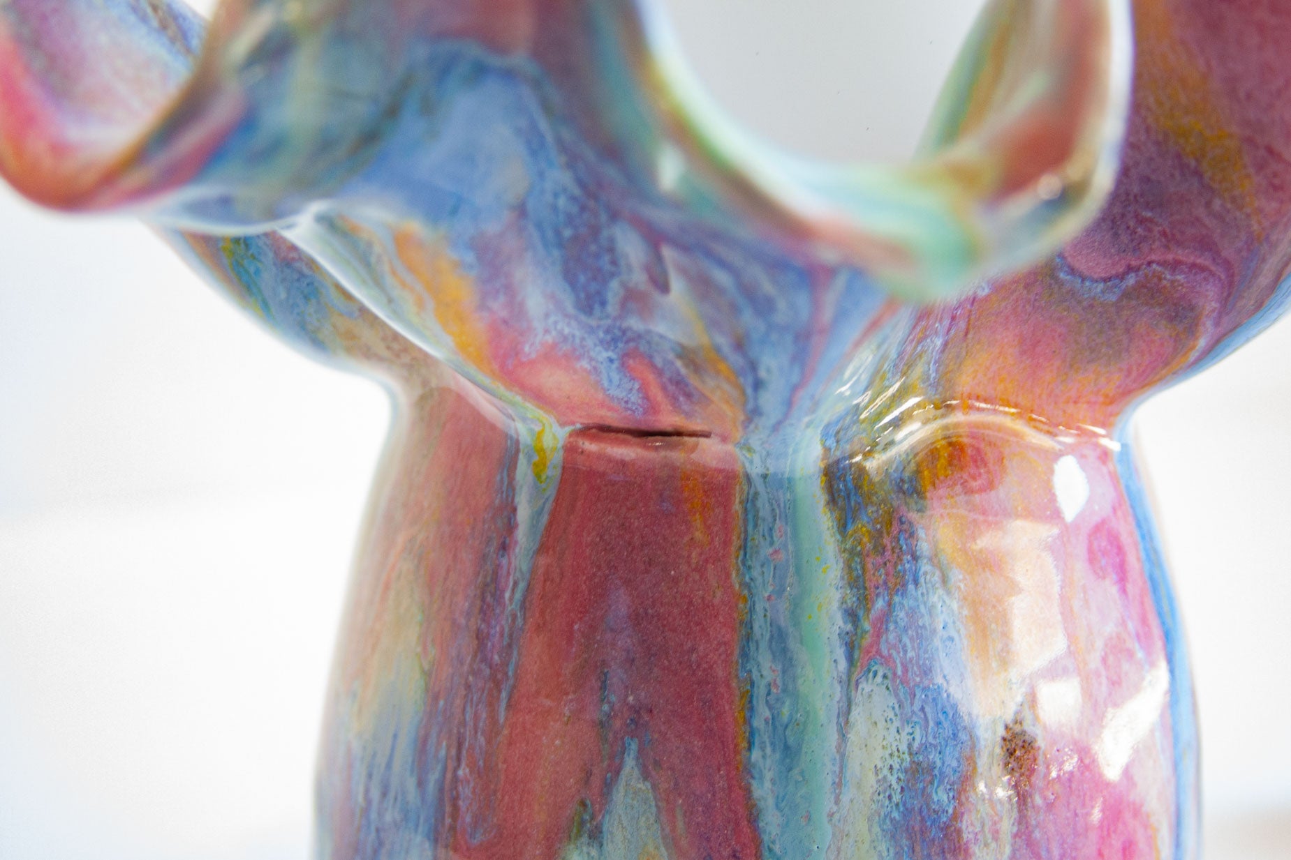 Close-up of a glossy ceramic vase with a marbled, fluid art pattern in vibrant shades of blue, pink, purple, and orange.