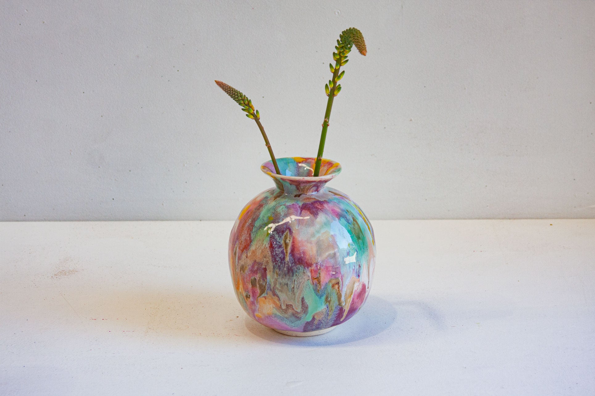 Colourful handmade ceramic moon jar with two flower stems.