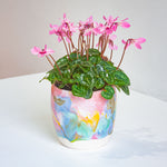 handmade ceramic planter on a table with pink flowering plant