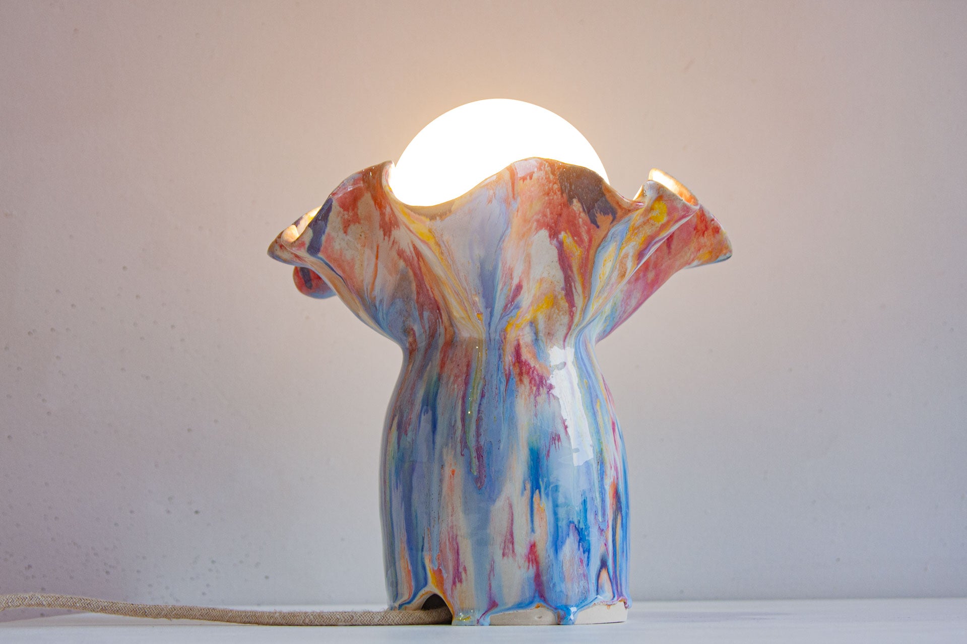 handmade ceramic table lamp shown with light on 