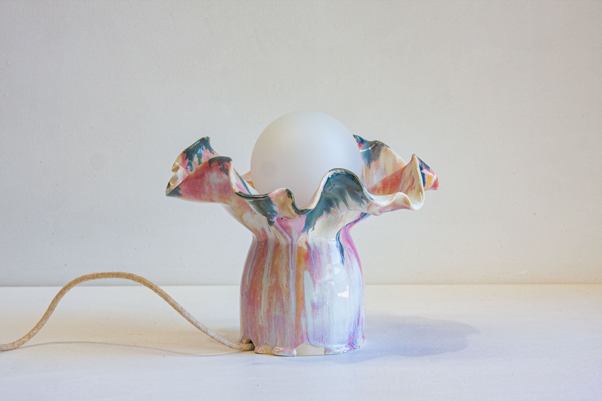 handmade ceramic table lamp glazed in a fluid drippy pink, peach and blue colour.