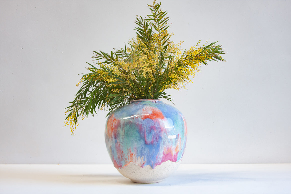 Handmade ceramic sculptural vase in bright vibrant colours with australian native flowers placed in it