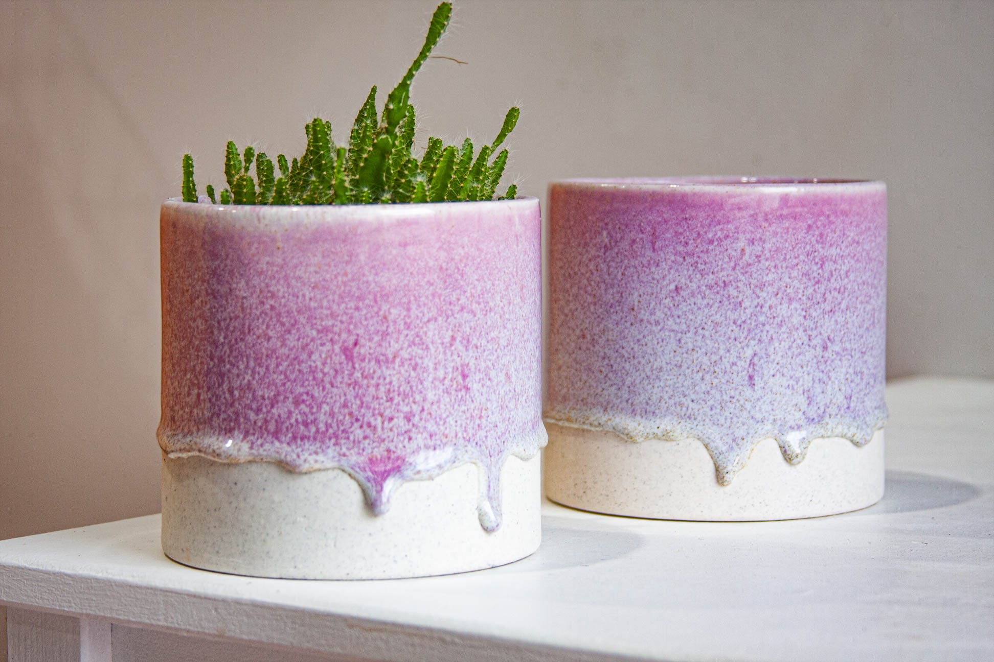 two speckled purple handmade ceramic planters on a table.