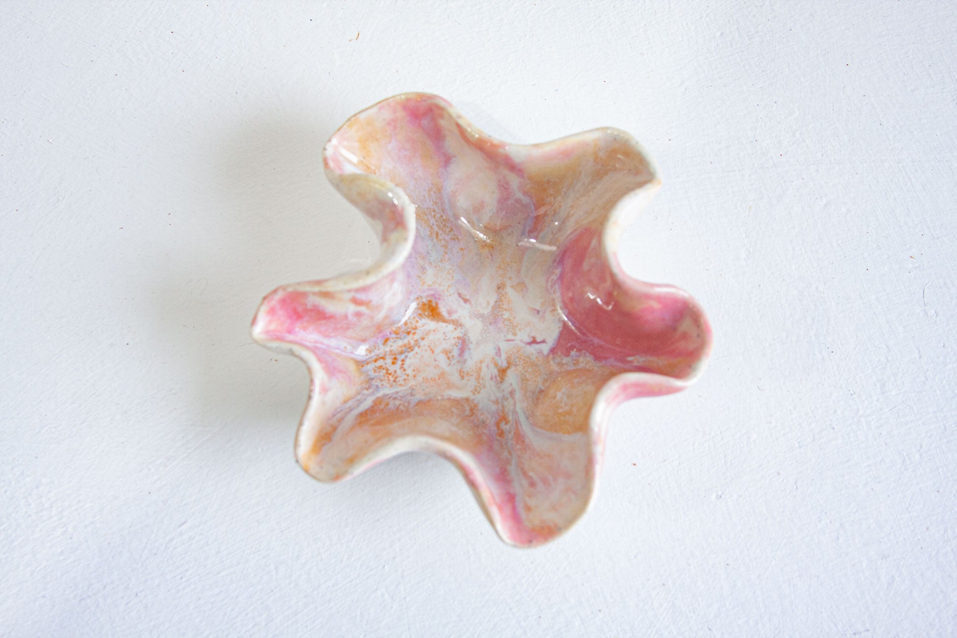 Marbled pink and orange star-shaped object on a white background