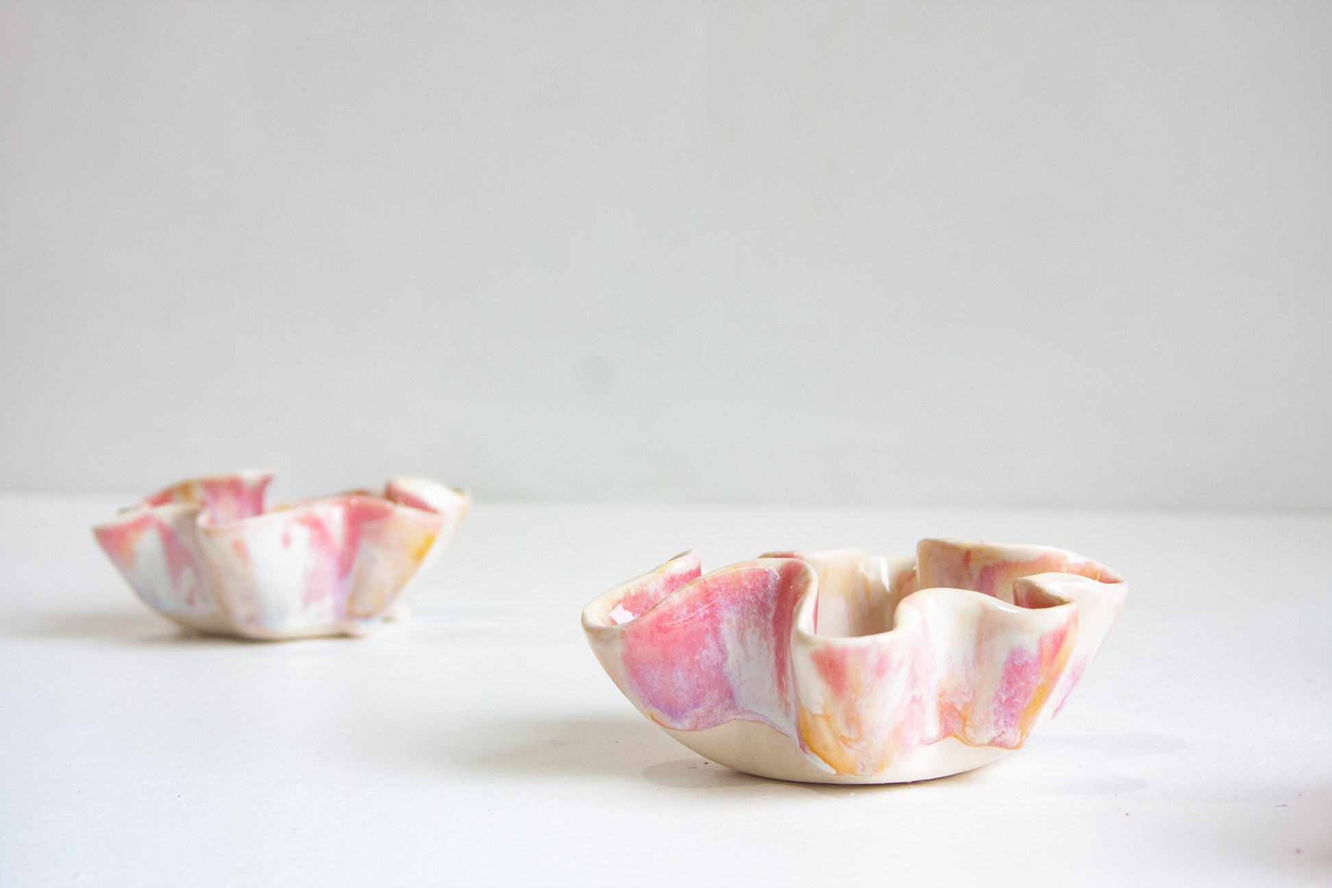 Two ceramic bowls with marbled pink and white design on a light gray background