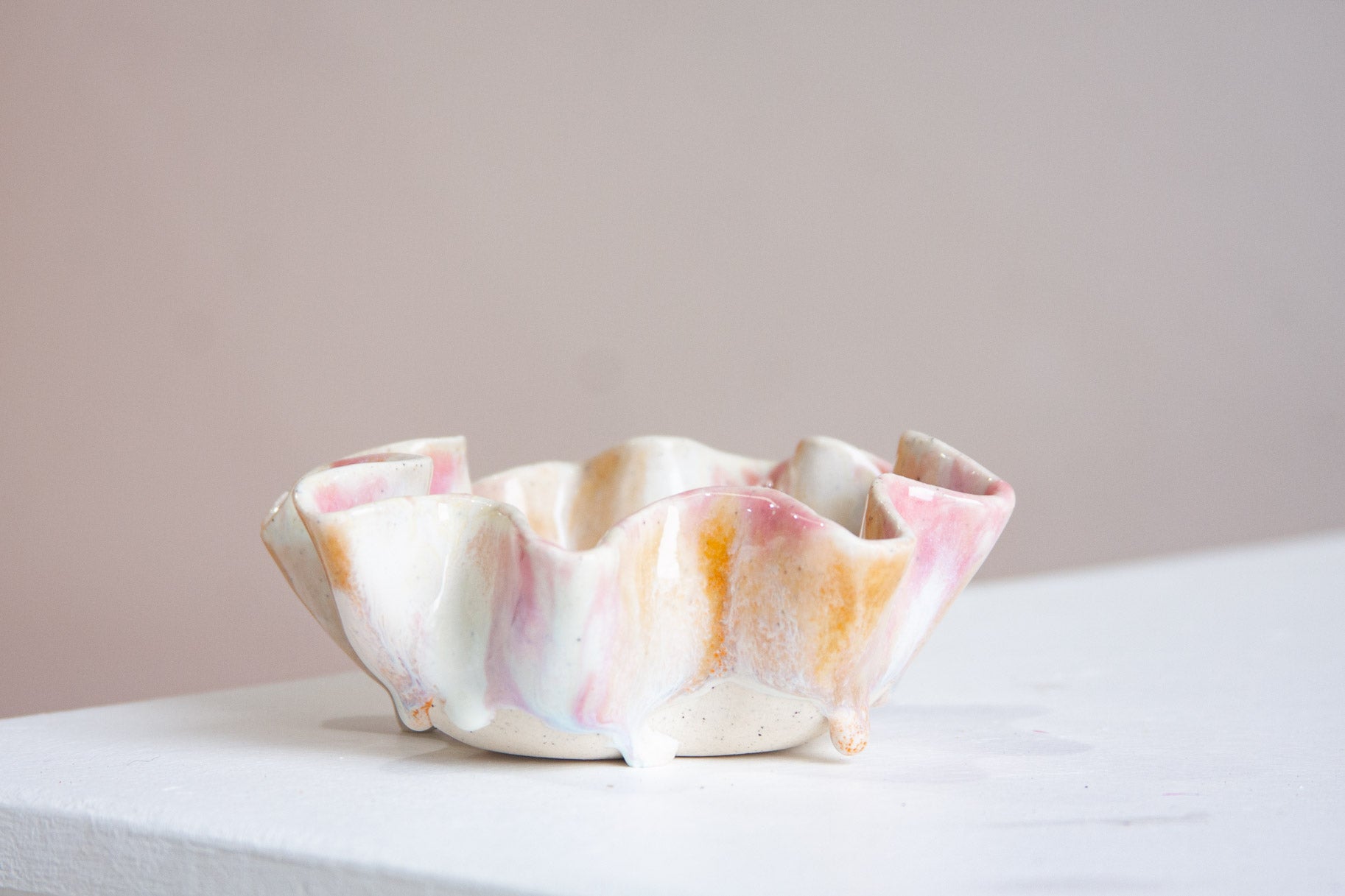 Ceramic bowl with pink and orange glaze on a white surface
