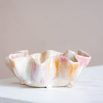 Ceramic bowl with pink and orange glaze on a white surface