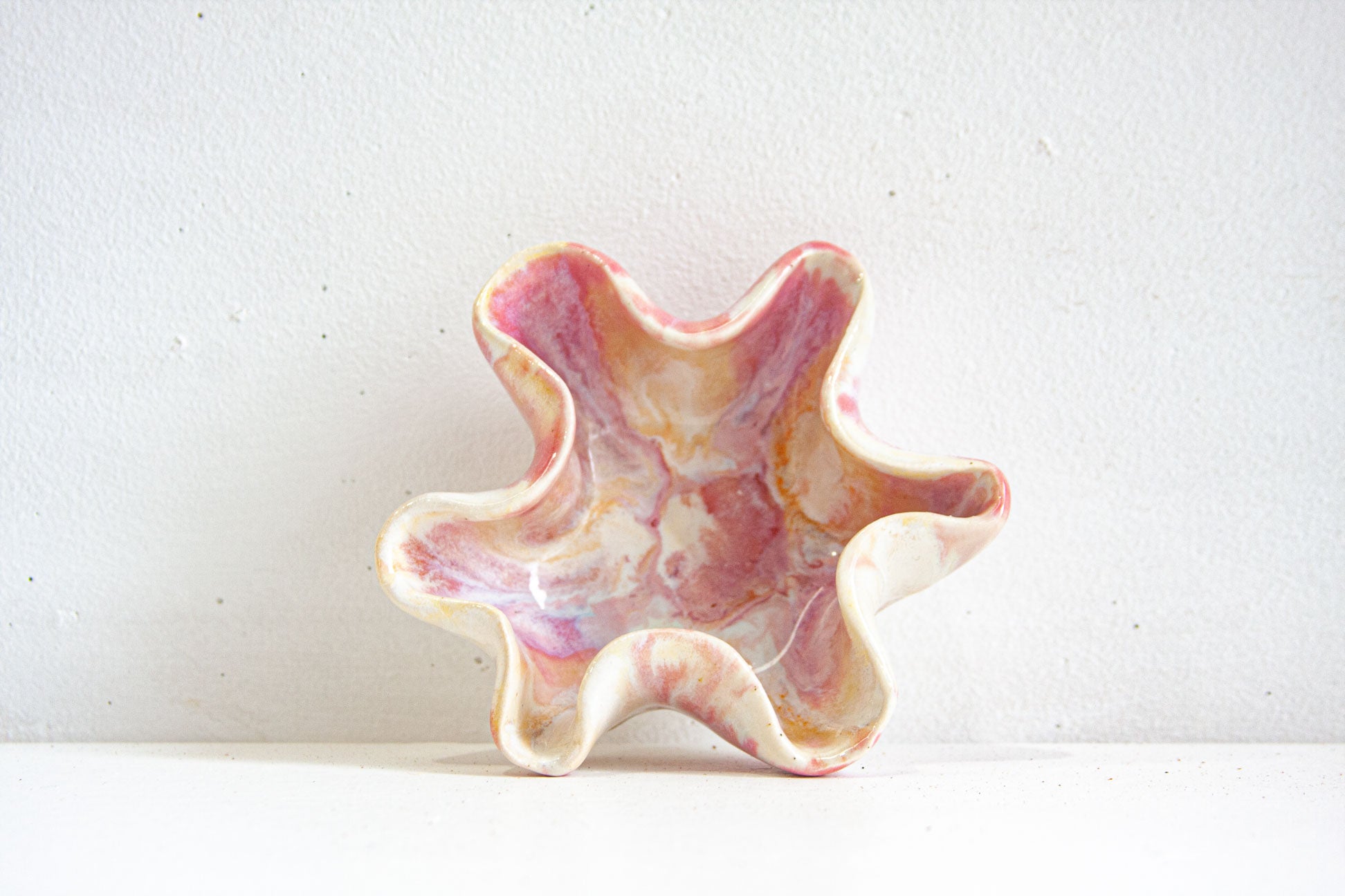 Pink and white starfish-shaped object on a light gray background