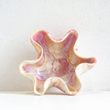 Pink and white starfish-shaped object on a light gray background