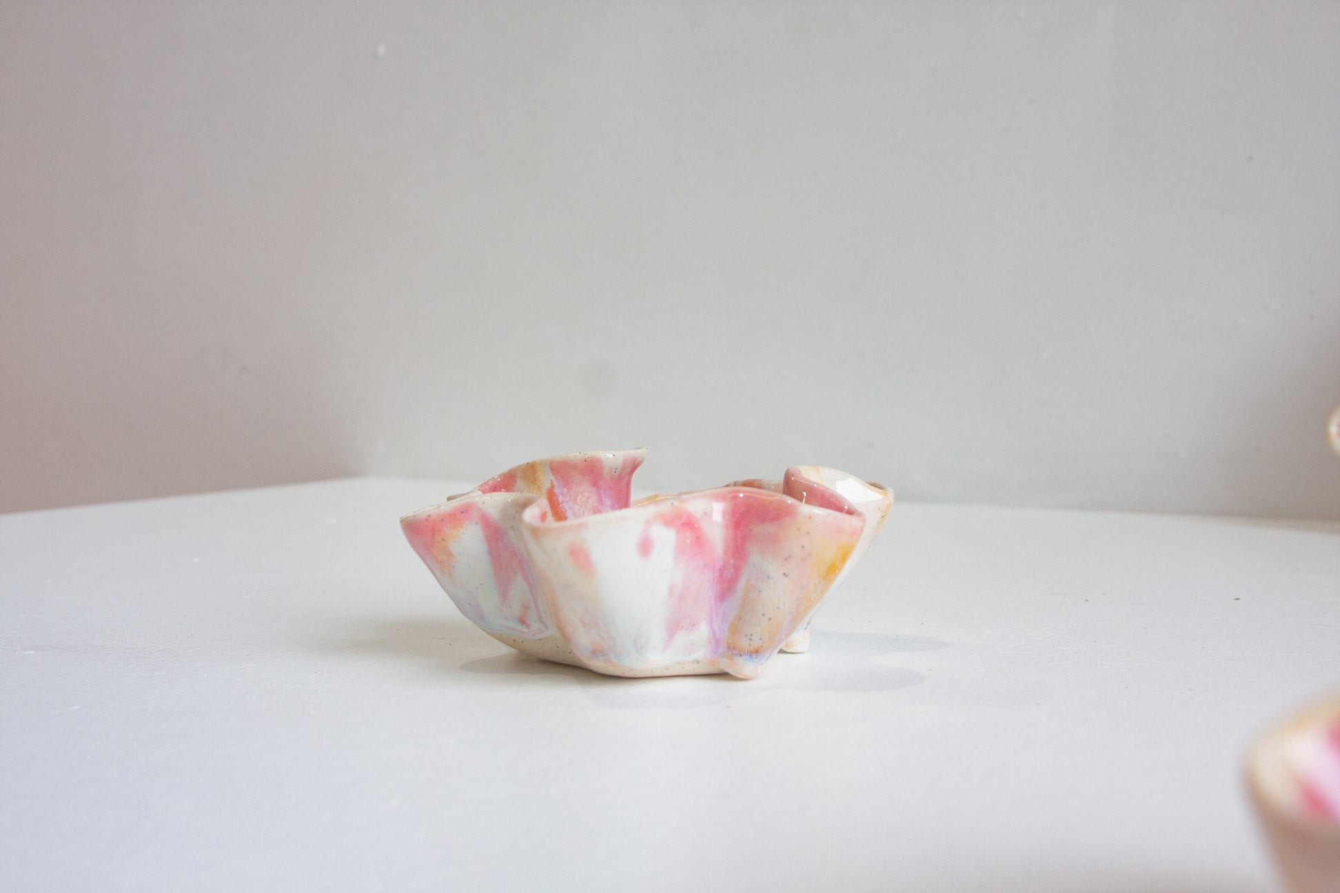 Marbled pink and white ceramic bowl on a light surface with a neutral background