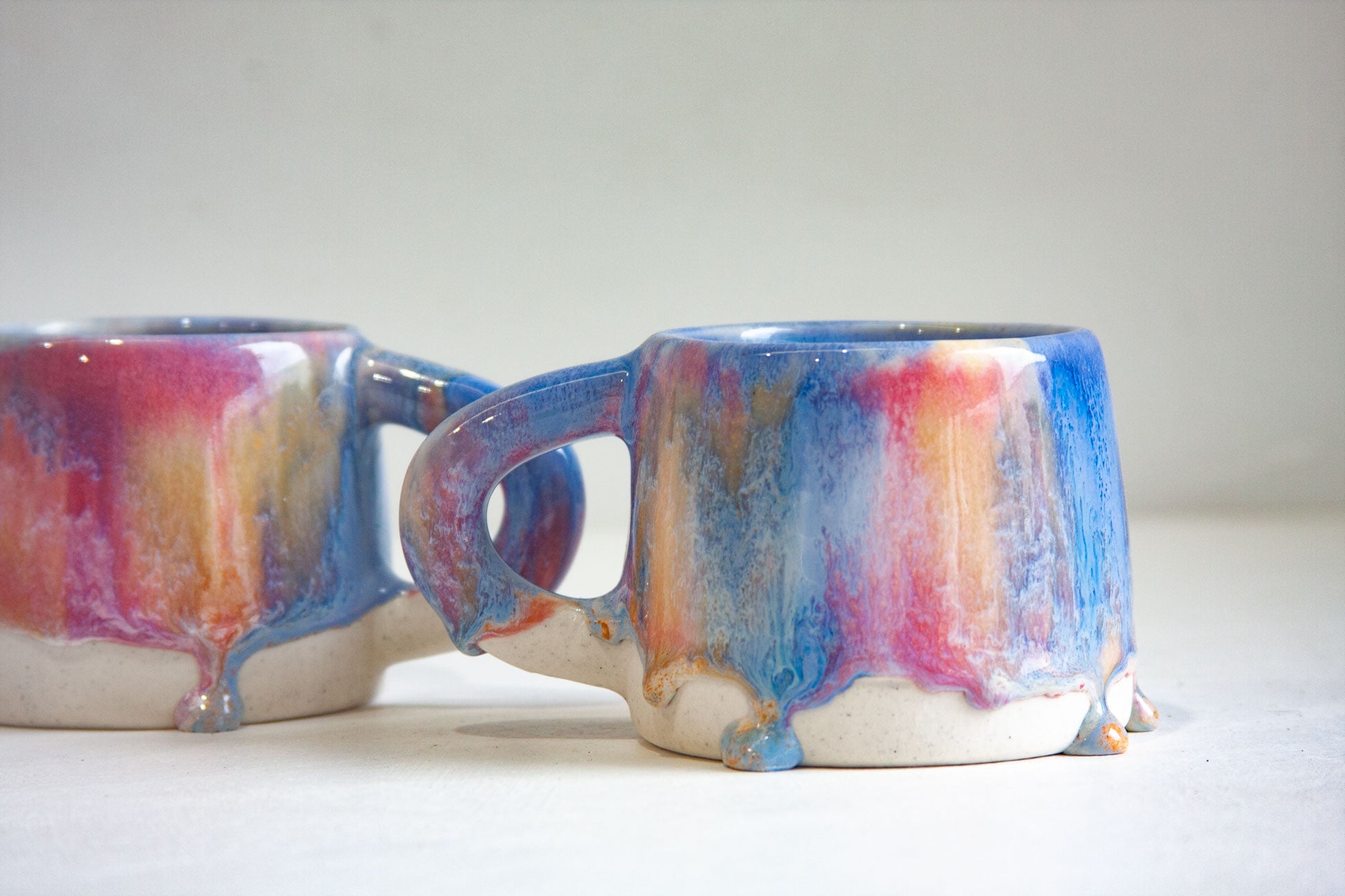 two handmade ceramic mugs glazed in pink, blue an peach