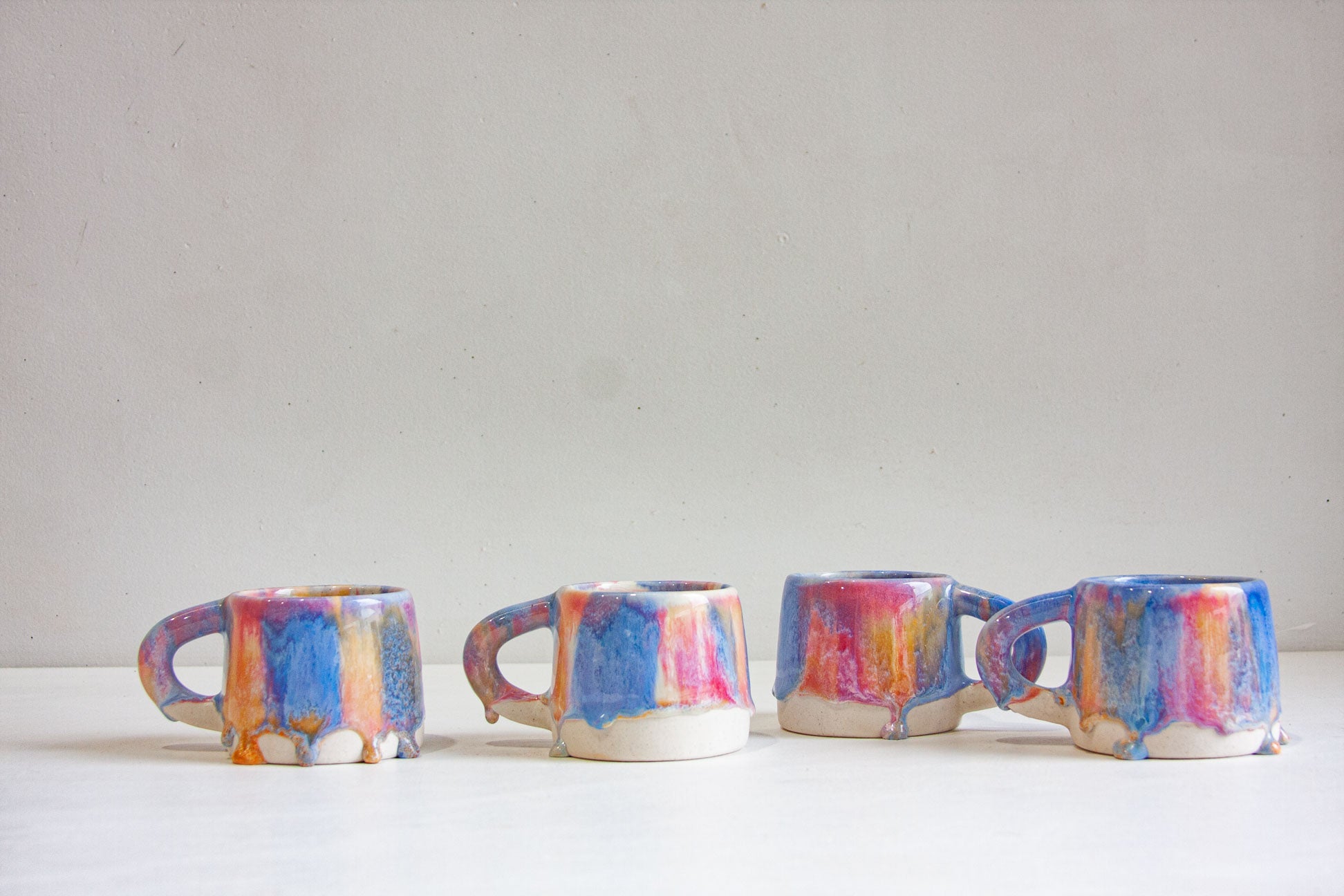 four handmade ceramic pink, peach and blue mugs