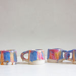 four handmade ceramic pink, peach and blue mugs