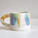 Ceramic mug with multicoloured handle on a white background