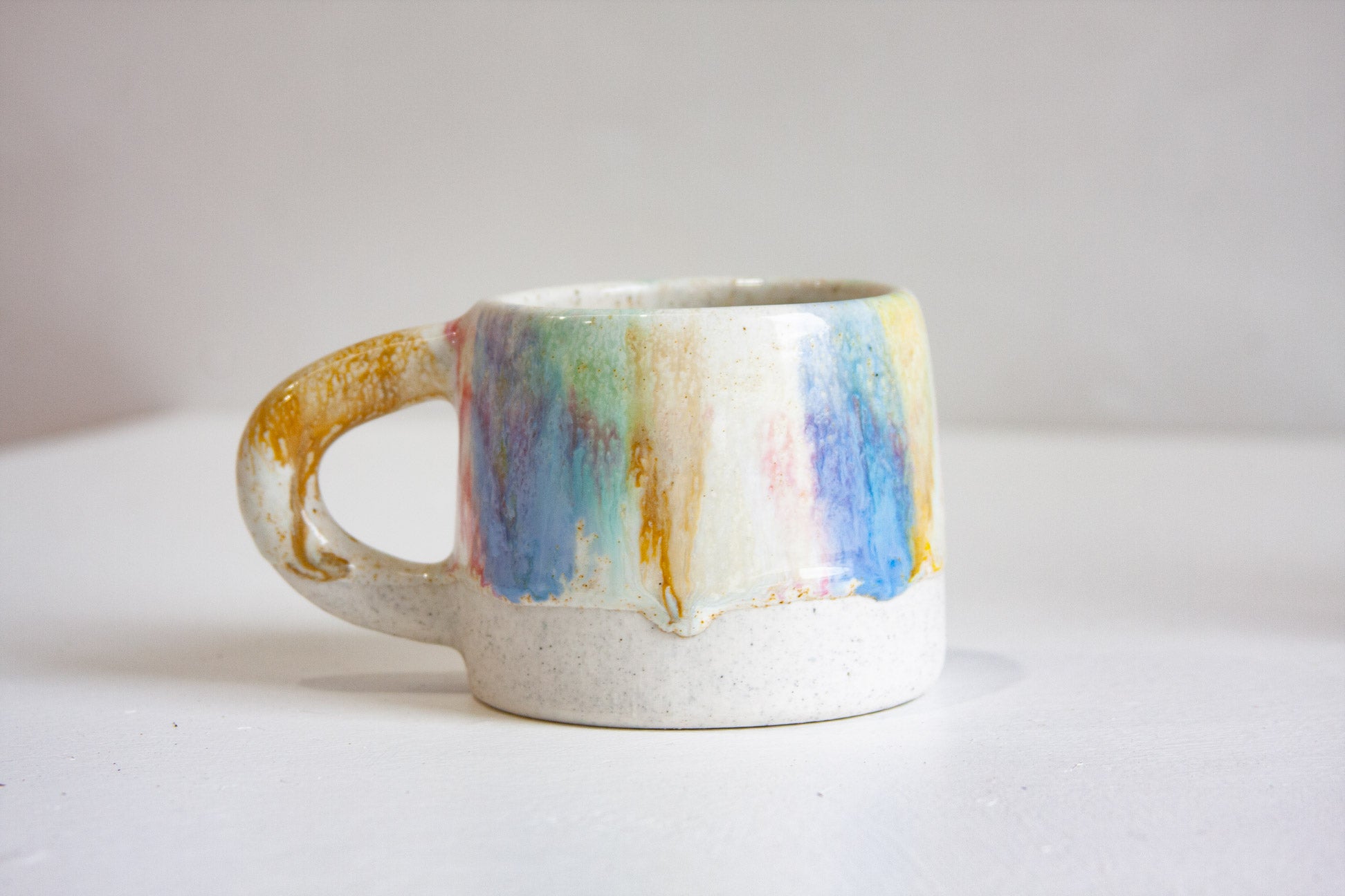 Ceramic mug with multicoloured handle on a white background