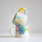 Two ceramic mugs with watercolour design stacked on a white background