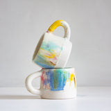 Two ceramic mugs with watercolour design stacked on a white background