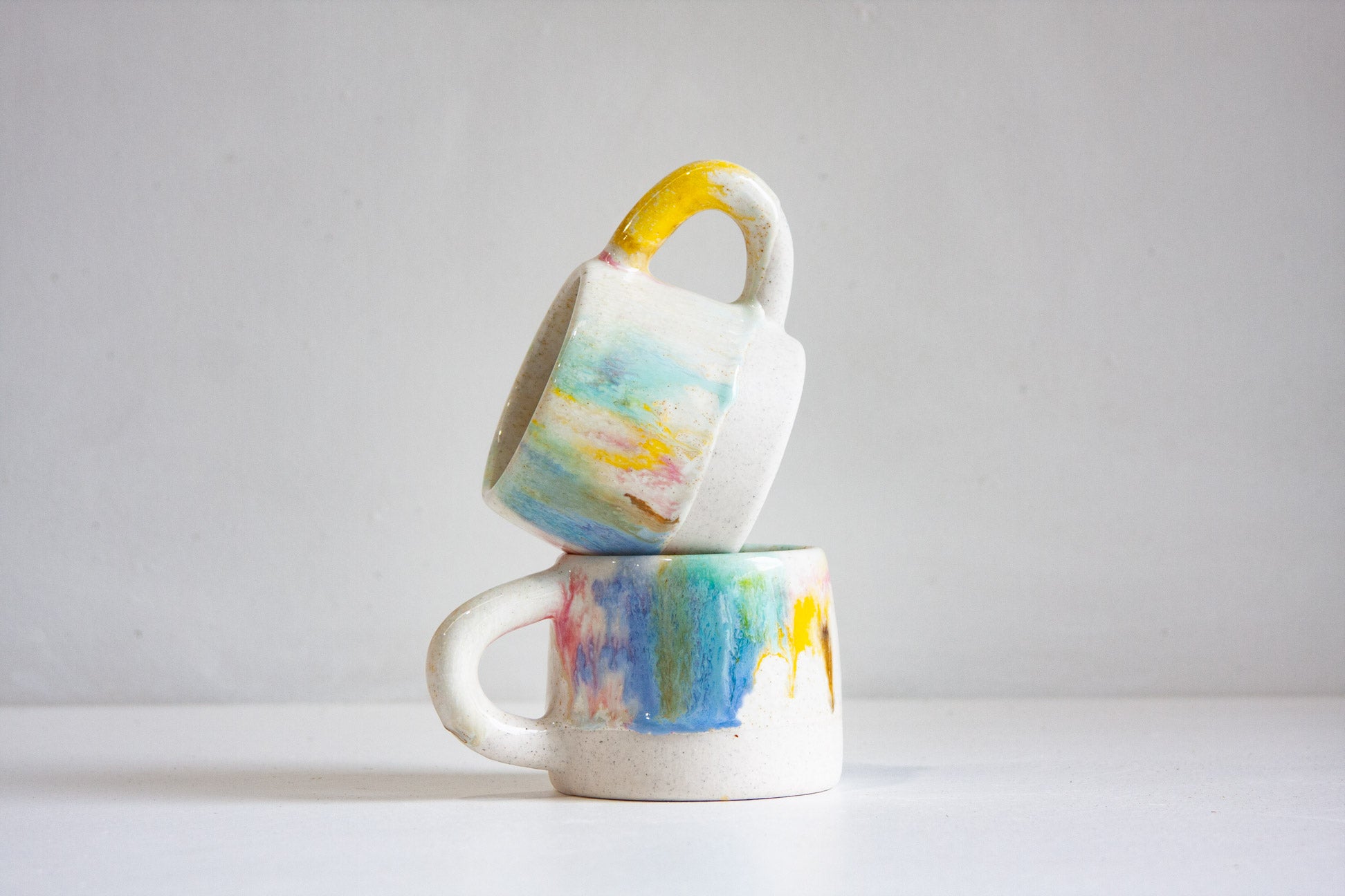 Two ceramic mugs with watercolour design stacked on a white background