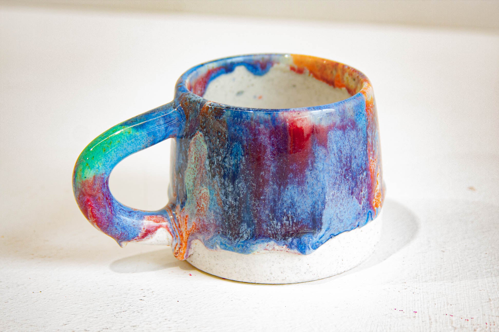 close up of blue, green, orange and pink handmade ceramic mug