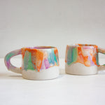 photo of two handmade ceramic mugs glazed in purple, green and orange mug 