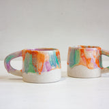 photo of two handmade ceramic mugs glazed in purple, green and orange mug 