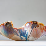 handmade ceramic oyster shaped platter glazed in blue, brown, peach and pink.